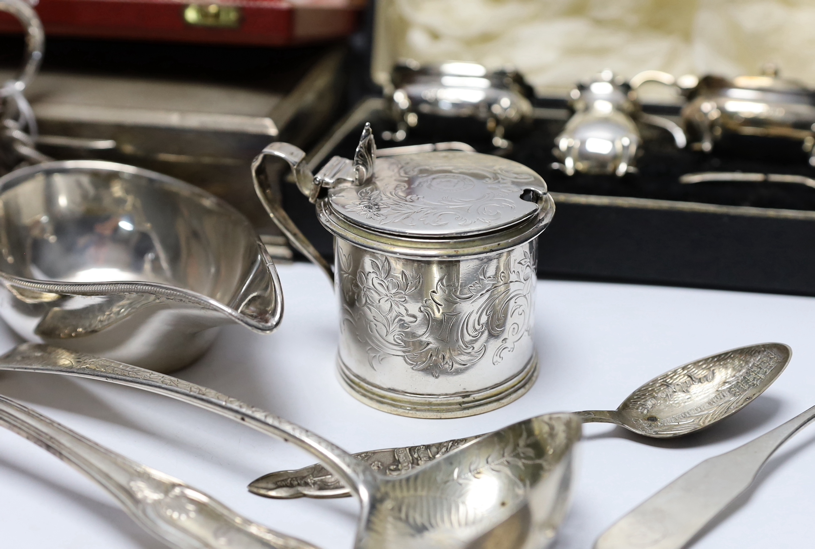 Sundry silver wares including a cigarette box and case, cased condiment set, cased pair of pepperettes and cased set of six teaspoons, sauceboat, Victorian mustard, Victorian mug with angular handle, nine items of flatwa